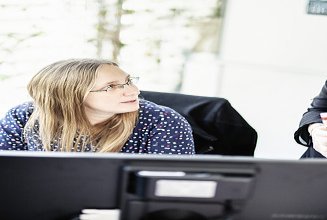 Foto zwei Mitarbeiterinnen im Büro vor Bildschirmen besprechen sich
