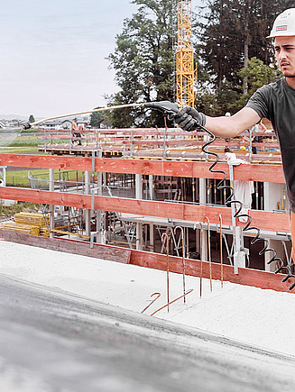 Ein Hochbaulehrling zieht frischen Beton glatt