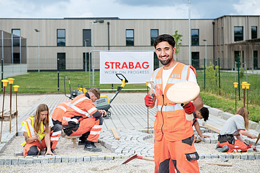 Foto Auszubildender vor zu pflasternder Fläche