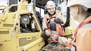 Foto zweier Lehrlinge vor Baumaschine