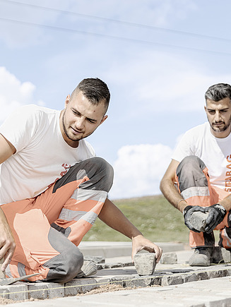 Foto zwei Bauarbeiter beim Pflastern einer Fläche