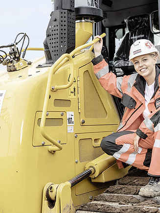 Foto Mitarbeiterin auf Baumaschine