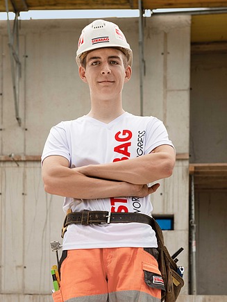 Bild eines Lehrlings auf der Baustelle vor einem Gebäude im Rohbau