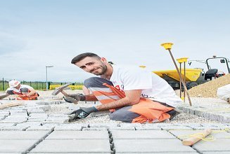 Foto Ein Lehrling verlegt Pflastersteine