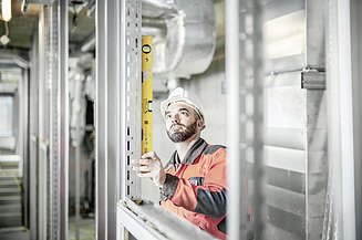 Foto Bauarbeiter kontrolliert eine Metallleiste mit Wasserwaage