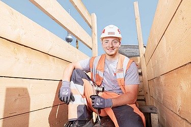 Foto Lehrling lehnt sich auf einen Spaten. 