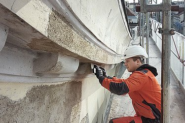 Foto ein Stuckateur beim Bearbeiten einer Fassade