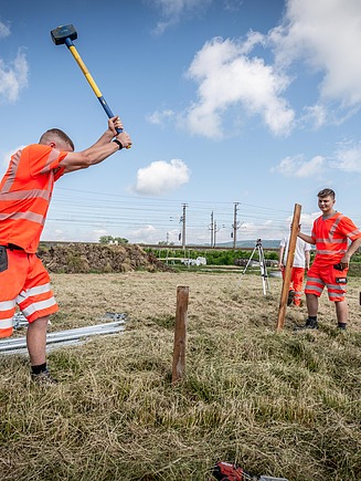 Foto zwei Lehrlinge auf dem Feld, der linke hält ein Werkzeug in den Händen