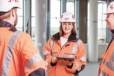 Foto ein Mitarbeiter und eine Mitarbeiterin beim Betrachten eines Bauplans