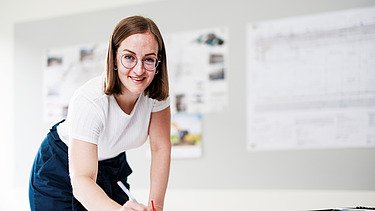 Foto ein Mitarbeiter vor zwei Bildschirmen mit Bauplänen