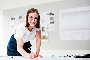Foto ein Mitarbeiter vor zwei Bildschirmen mit Bauplänen